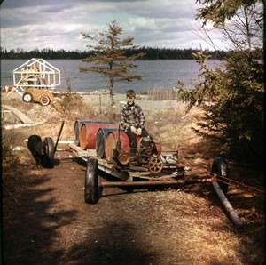 Ricky riding fuel tanks from the beach to the Money Pit area. The tanks were loaded on the boat float which was rigged to pull itself up the hill.